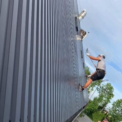 Pracownik przy malowaniu dachu z blachy trapezowej