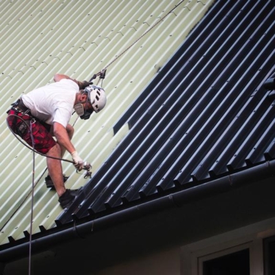 Pracownik w trakcie malowania dachu blaszanego z blachy trapezowej